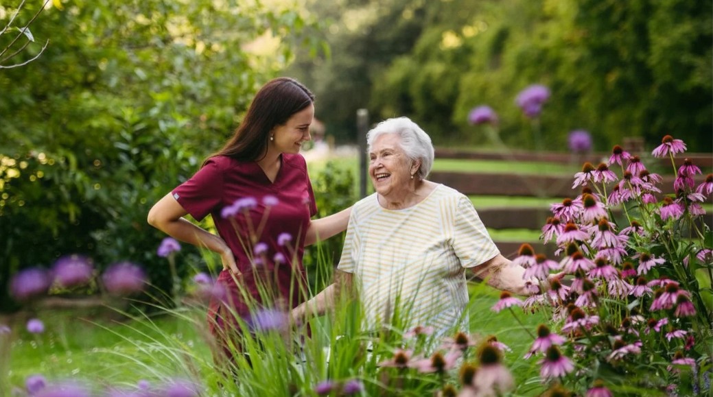 elderly woman walking in garden with caregiver