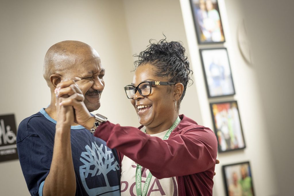 Female black caregiver dancing with elderly male black patient.