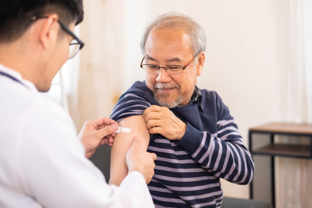 Elderly man getting bandaid after shot. Doctor or nurse treating senior.